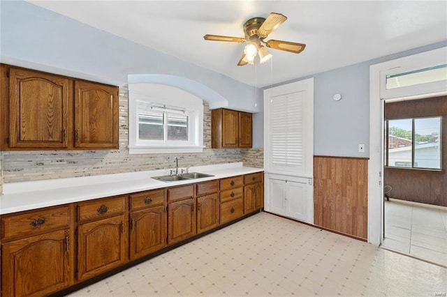 kitchen with sink, a wealth of natural light, wooden walls, and ceiling fan