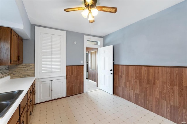 kitchen featuring ceiling fan, sink, and wooden walls