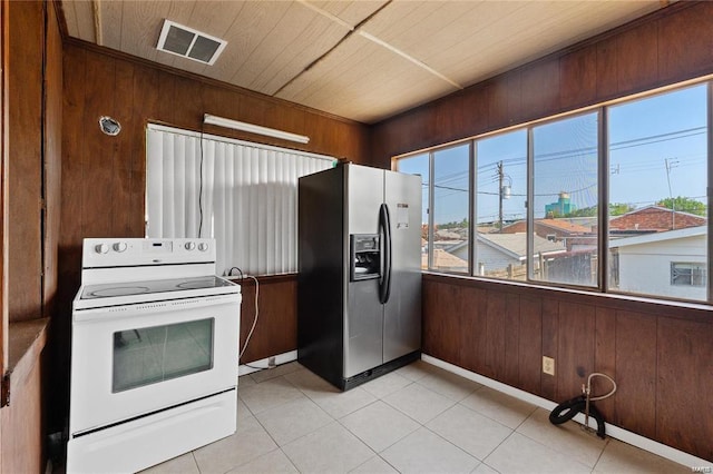 kitchen with light tile patterned floors, wood walls, white electric range oven, and stainless steel refrigerator with ice dispenser