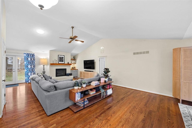 living room with french doors, vaulted ceiling, a brick fireplace, and hardwood / wood-style floors