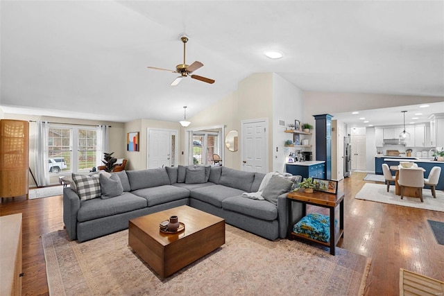 living room featuring light hardwood / wood-style flooring, ceiling fan, and vaulted ceiling