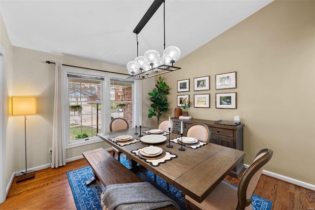 dining space with light wood-type flooring, a chandelier, and vaulted ceiling