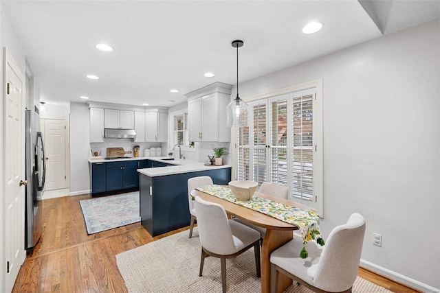 kitchen with white cabinets, hanging light fixtures, blue cabinets, and light hardwood / wood-style flooring