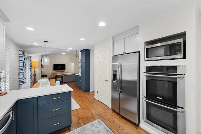 kitchen featuring stainless steel appliances, white cabinets, blue cabinets, vaulted ceiling, and light wood-type flooring