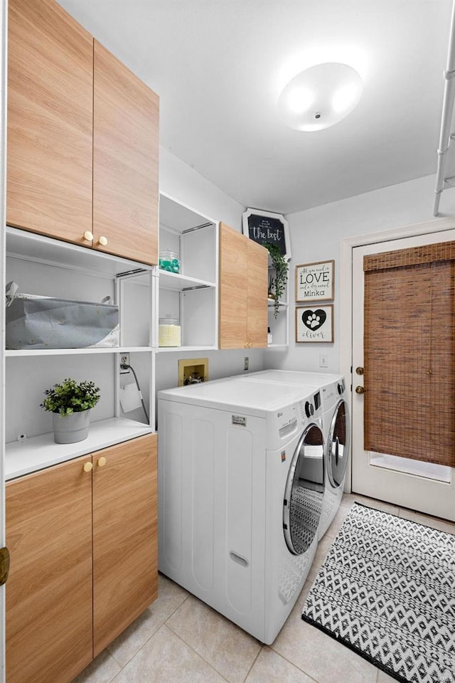 laundry area with light tile patterned floors, washer and dryer, and cabinets