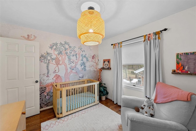 bedroom with a crib and dark wood-type flooring