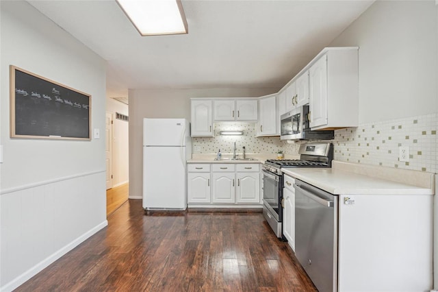 kitchen with dark hardwood / wood-style floors, white cabinetry, sink, decorative backsplash, and stainless steel appliances