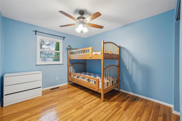 bedroom with ceiling fan, light hardwood / wood-style flooring, and a textured ceiling