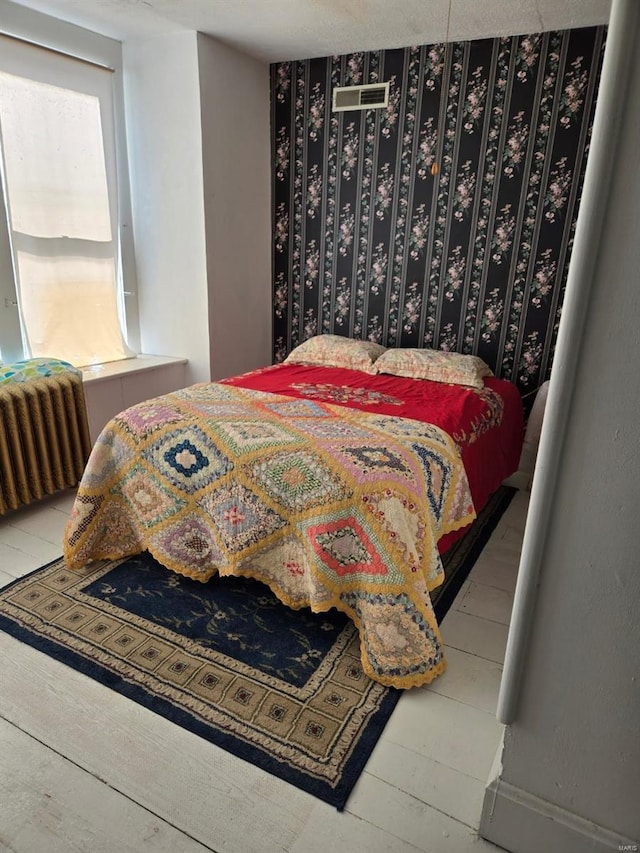 bedroom with wood-type flooring and radiator heating unit