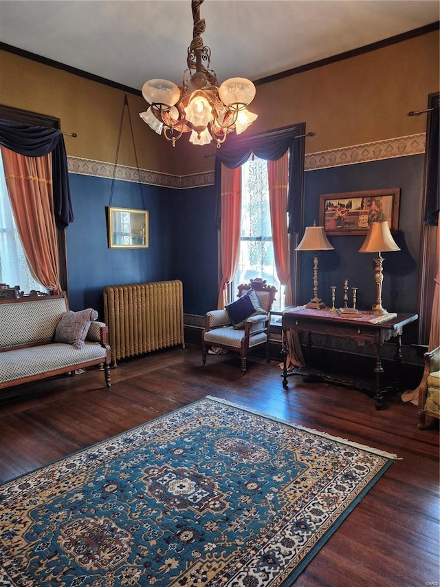 sitting room with hardwood / wood-style flooring, ornamental molding, radiator heating unit, and a notable chandelier