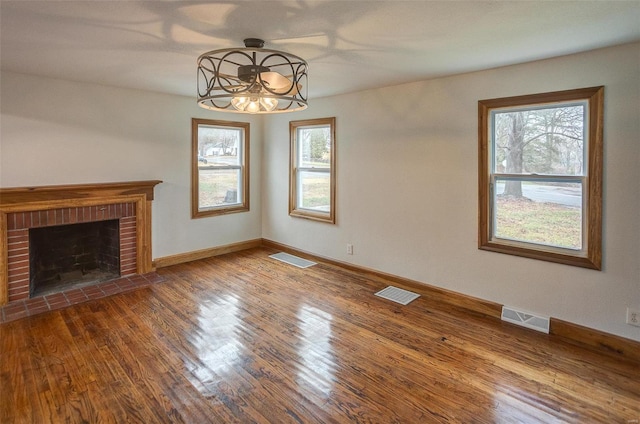 unfurnished living room with hardwood / wood-style flooring and a brick fireplace