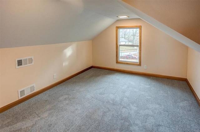 additional living space featuring vaulted ceiling and carpet flooring