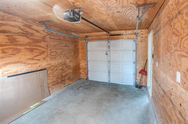 garage with a garage door opener, wooden ceiling, and wood walls