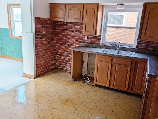 kitchen featuring brick wall, sink, and a wealth of natural light