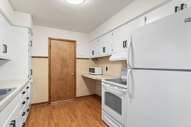 kitchen featuring tile walls, white appliances, light hardwood / wood-style floors, and white cabinets