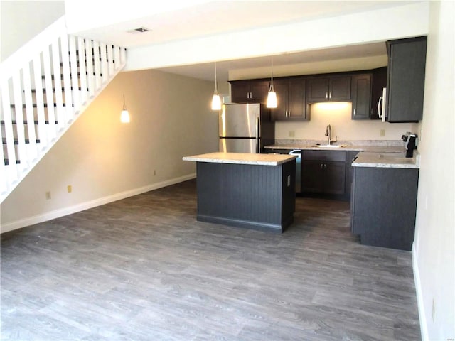 kitchen featuring dark wood-type flooring, sink, hanging light fixtures, a kitchen island, and stainless steel appliances