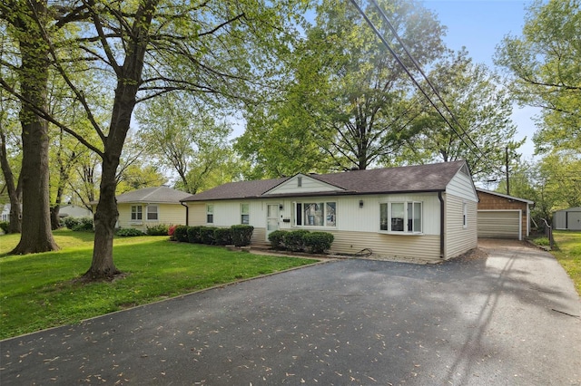 single story home with a detached garage, a front yard, and an outbuilding