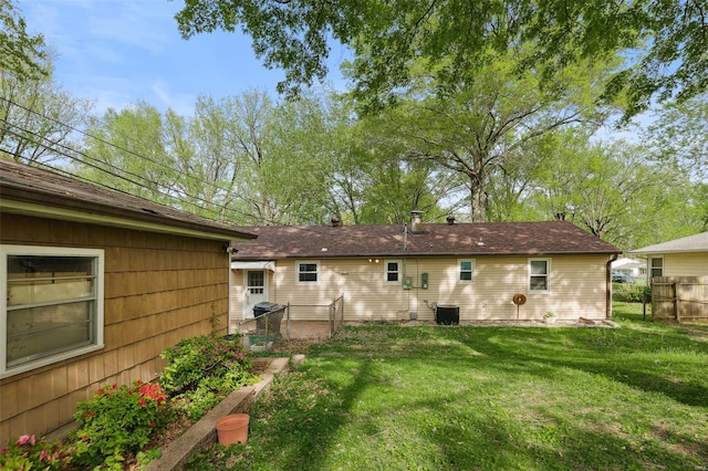 rear view of property with fence and a lawn