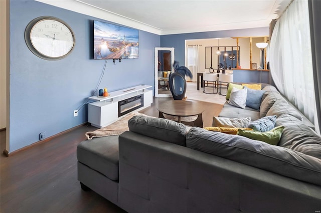 living area with baseboards, wood finished floors, and a glass covered fireplace