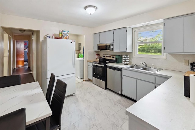 kitchen featuring a sink, stainless steel appliances, gray cabinets, backsplash, and light countertops