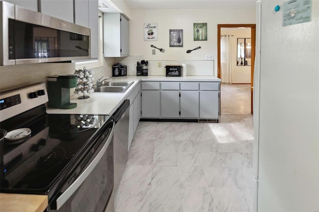 kitchen featuring gray cabinets, stainless steel appliances, light countertops, marble finish floor, and a sink