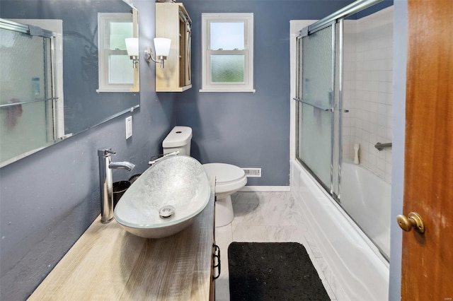 full bath with a sink, combined bath / shower with glass door, baseboards, toilet, and marble finish floor
