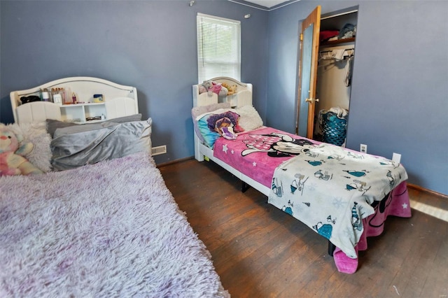 bedroom with baseboards, wood finished floors, and a closet