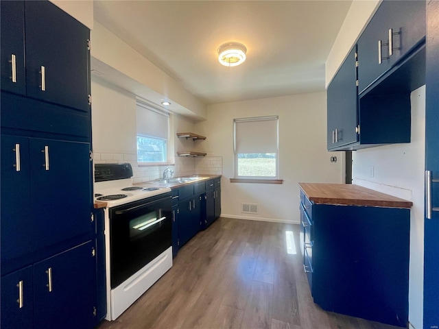 kitchen with blue cabinets, wooden counters, light wood-type flooring, range with electric cooktop, and decorative backsplash