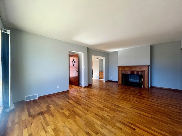 unfurnished living room featuring a brick fireplace and hardwood / wood-style floors