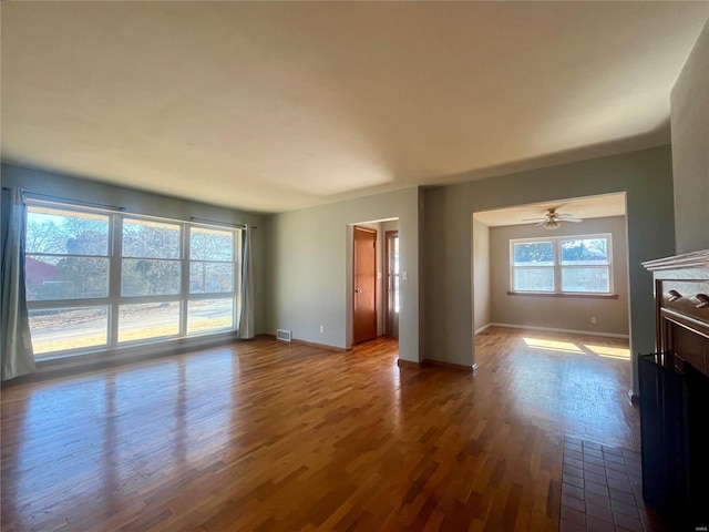 unfurnished living room featuring ceiling fan, a wealth of natural light, and wood-type flooring