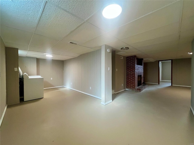 basement featuring washer / dryer, a brick fireplace, and a drop ceiling