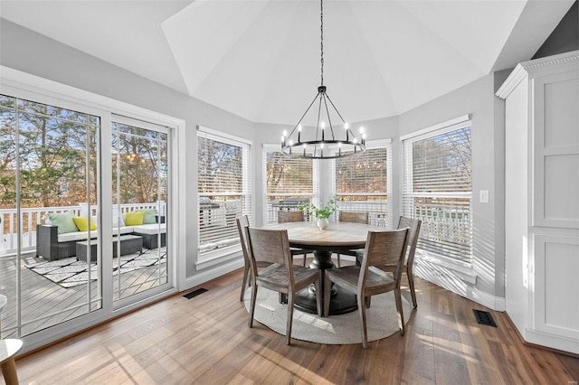 dining room featuring an inviting chandelier, vaulted ceiling, and hardwood / wood-style floors