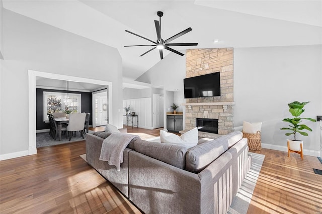 living room with a stone fireplace, high vaulted ceiling, ceiling fan, and hardwood / wood-style flooring