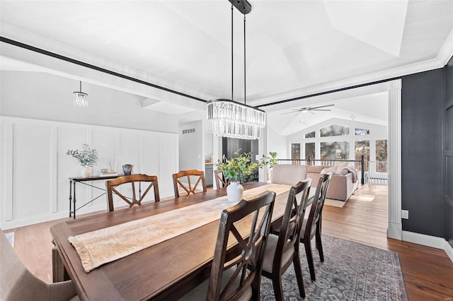 dining space featuring hardwood / wood-style floors, ceiling fan with notable chandelier, and vaulted ceiling