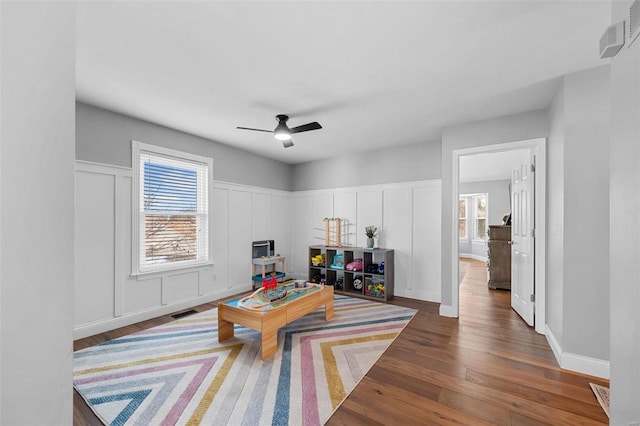 recreation room featuring a healthy amount of sunlight, dark wood-type flooring, and ceiling fan