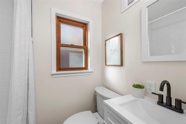 bathroom featuring walk in shower, vanity, and toilet