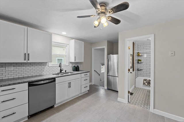 kitchen featuring sink, ceiling fan, white cabinetry, stainless steel appliances, and decorative backsplash