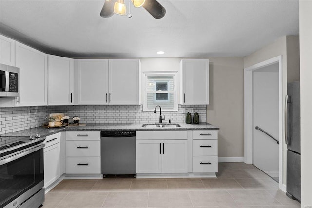 kitchen with light tile patterned flooring, appliances with stainless steel finishes, sink, white cabinets, and backsplash