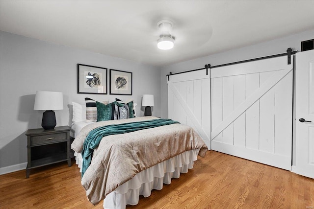 bedroom with a barn door and hardwood / wood-style floors