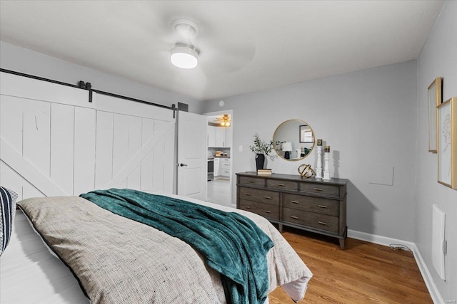 bedroom featuring light hardwood / wood-style flooring, a barn door, and ceiling fan