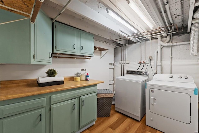 laundry room featuring cabinets, light hardwood / wood-style flooring, and washing machine and clothes dryer