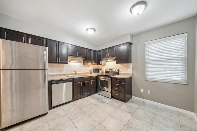 kitchen with light stone counters, sink, backsplash, and appliances with stainless steel finishes