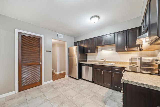 kitchen with light tile patterned flooring, appliances with stainless steel finishes, tasteful backsplash, sink, and dark brown cabinets