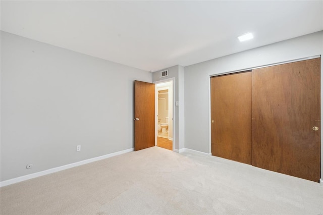 unfurnished bedroom with light colored carpet and a closet