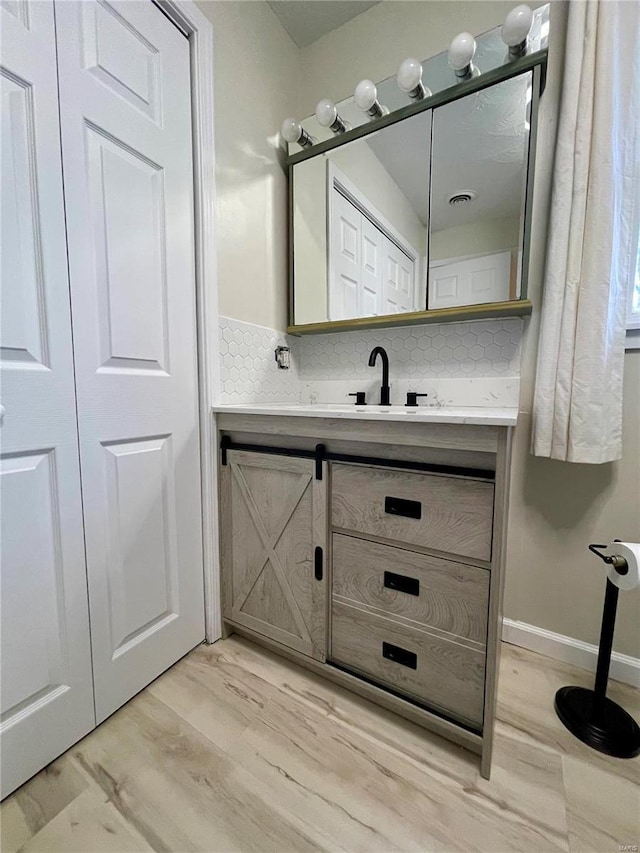 bathroom with vanity, hardwood / wood-style floors, and decorative backsplash