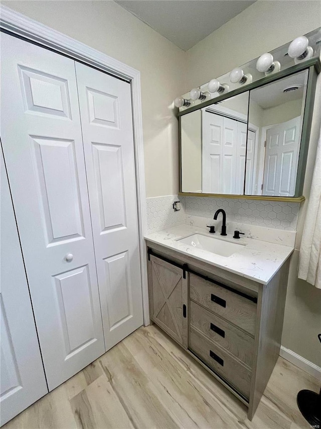 bathroom with vanity, wood finished floors, a closet, and backsplash