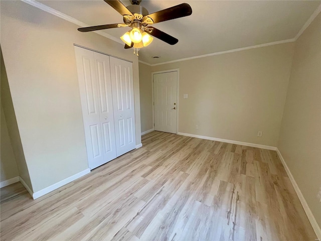 unfurnished bedroom featuring crown molding, baseboards, light wood-style flooring, a closet, and a ceiling fan