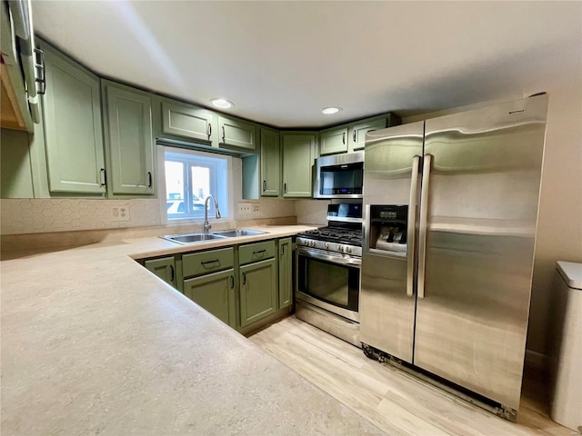 kitchen featuring sink, green cabinets, light hardwood / wood-style floors, and appliances with stainless steel finishes