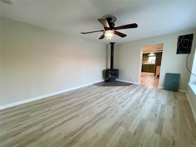 unfurnished living room featuring light hardwood / wood-style floors, ceiling fan, and a wood stove