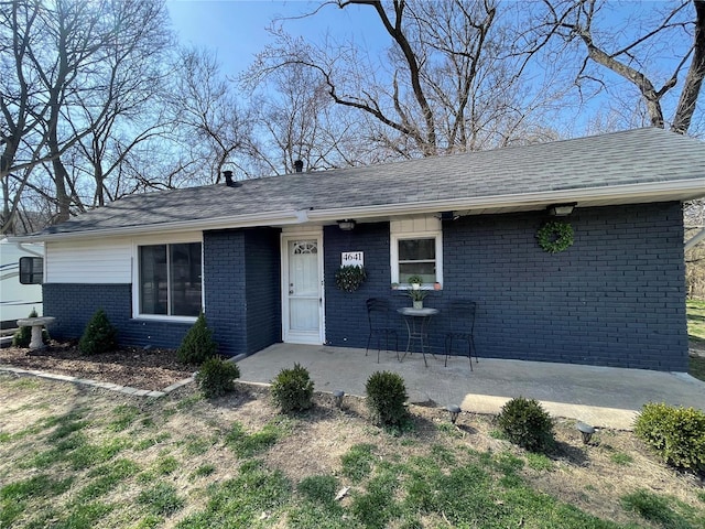 ranch-style house featuring brick siding and a shingled roof